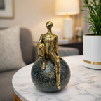 Golden Abstract Figurine Sitting on Globe