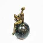 Golden Abstract Figurine Sitting on Globe