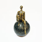 Golden Abstract Figurine Sitting on Globe