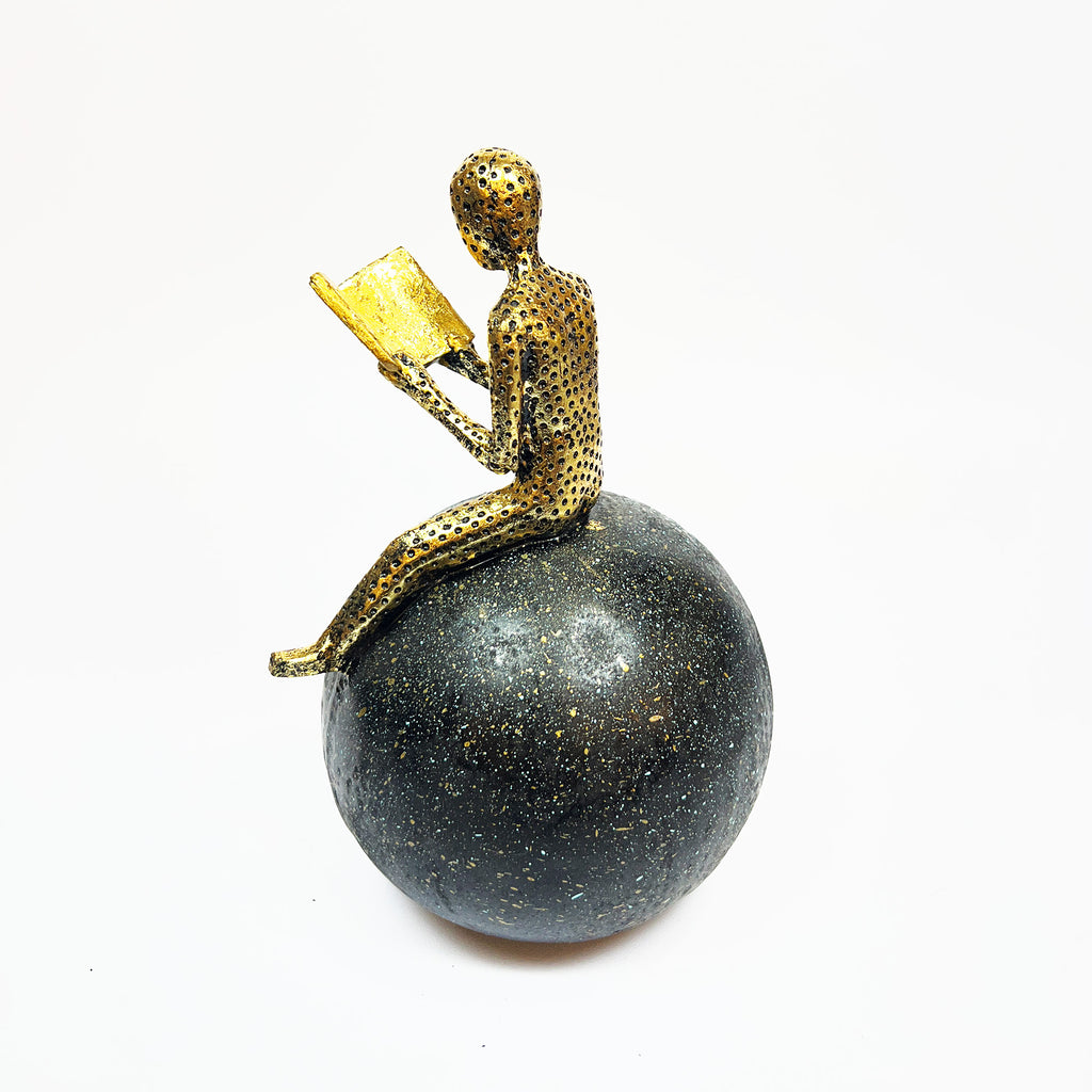 Golden Figurine Reading a Book on Globe
